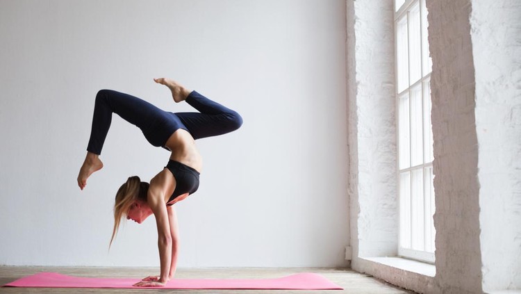 Sporty yogi girl practices yoga asana, Scorpion Pose Vrischikasana, forearm stand, inverted backbend pose.