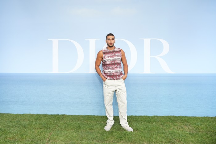Model Younes Bendjima yang juga mantan kekasih Kourtney Kardashian memilih bergaya sporty dengan padanan sleeveless top, celana putih, dan sandal kolaborasi Dior x Birkenstock. Foto: Getty Images For Christian Dior/Francois Durand