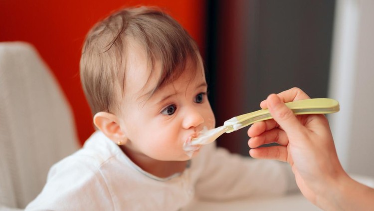 anak makan yoghurt Sweet child in highchair being fed by his mom