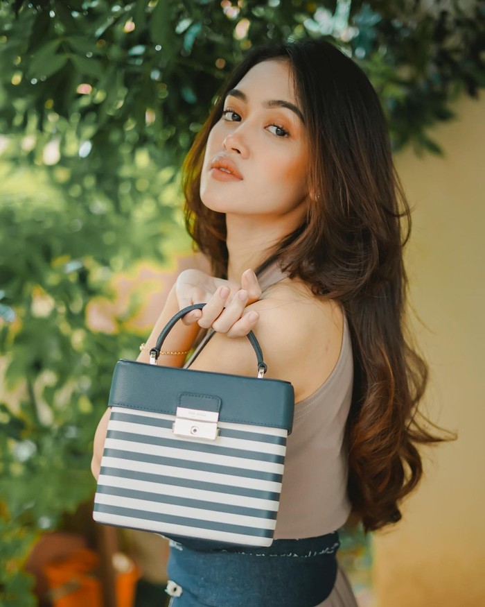 Corak garis bisa jadi statement yang bold pada tas bersiluet klasik. Seperti pada model Voyage Striped Small Top-Handle Bag dari Kate Spade New York yang jadi pilihan Prinsa Mandagie. Foto: Instagram prinsamandagie