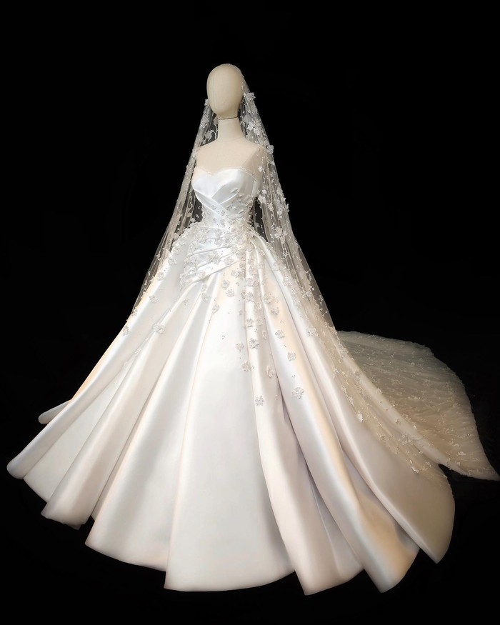 Bustier ballgown ditambah veil berwarna putih membuatmu tampil layaknya princess. Padu padan bunga 3D handmade yang melingkari gaun ini semakin menambah kesan estetik. Walau dengan makeup minimal, tampilan pemakainya tetap bakal memesona! (Foto: Instagram/Monica Ivena)