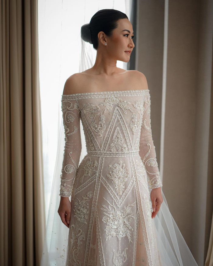 Gaun model off-the-shoulder bakal menonjolkan area bahumu yang cantik. Kesan 'sedikit terbuka' ini teratasi dengan lengan panjang, tambah cantik dengan hiasan manik dan kristal. Hari bahagiamu bakal makin bersinar! (Foto: Instagram/Hian Tjen)