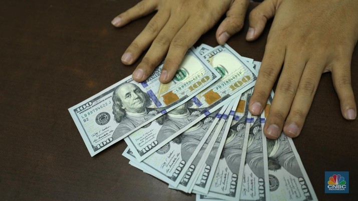 Pekerja memperlihatkan uang dolar di salah satu gerai money changer di Jakarta, Senin (4/7/2022). (CNBC Indonesia/ Tri Susilo)