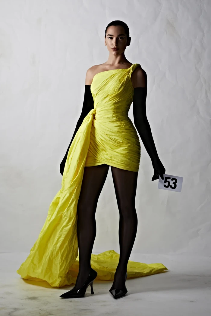 Dua Lipa tampil anggun dalam balutan mini dress aksen train saat jadi model fashion show Balenciaga. Sebelumnya ia juga pernah tampil di peragaan Versace pada tahun 2021. Foto: courtesy of Balenciaga