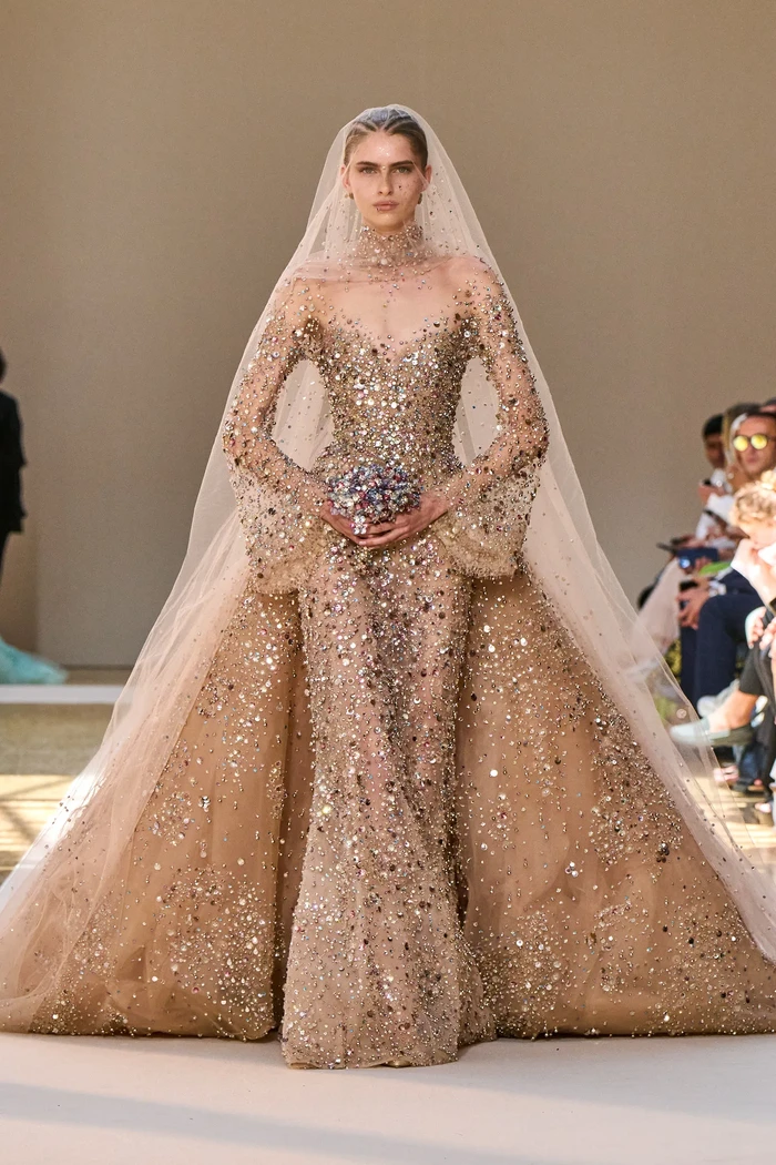 Seperti biasa, fashion show koleksi couture dari Elie Saab ditutup oleh gaun pengantin. Kali ini tampil gaun lengan panjang berbahan transparan berhiaskan kristal dan aksen train. Foto: Filippo Fior/Gorunway/Vogue