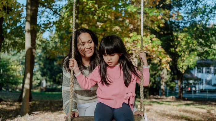 Autistic korean girl on a swing and her mother supporting her