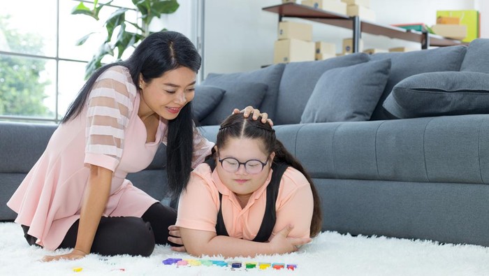 Autistic cute girl practicing connecting the color sticks at home while her mom kept watching nearby. Training for intelligence restoration for children with autism or aphasia kids.