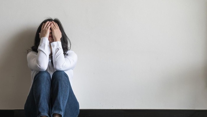 Anxiety disorder menopause woman, stressful depressed emotional person with mental health illness, headache and migraine sitting feeling bad sadly with back against wall on the floor in domestic home