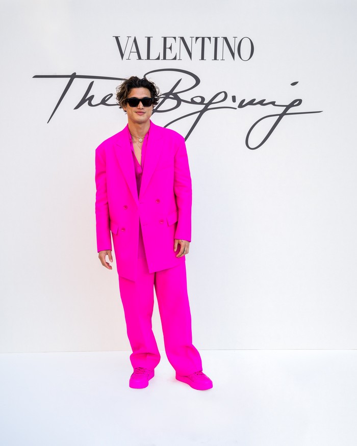 Charles Melton jadi aktor lain yang memakai busana warna yang diberi nama Pink PP tersebut. Menonton fashion show Valentino ia memilih setelan jas oversized dan sneakers. Foto: ALFONSO CATALANO