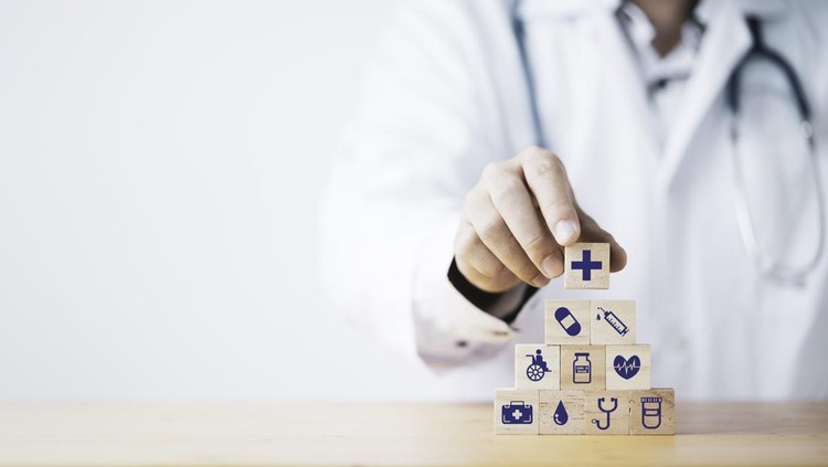 Doctor putting and stacking wooden block cube which print screen health care and medical icons for healthy and wellness concept.
