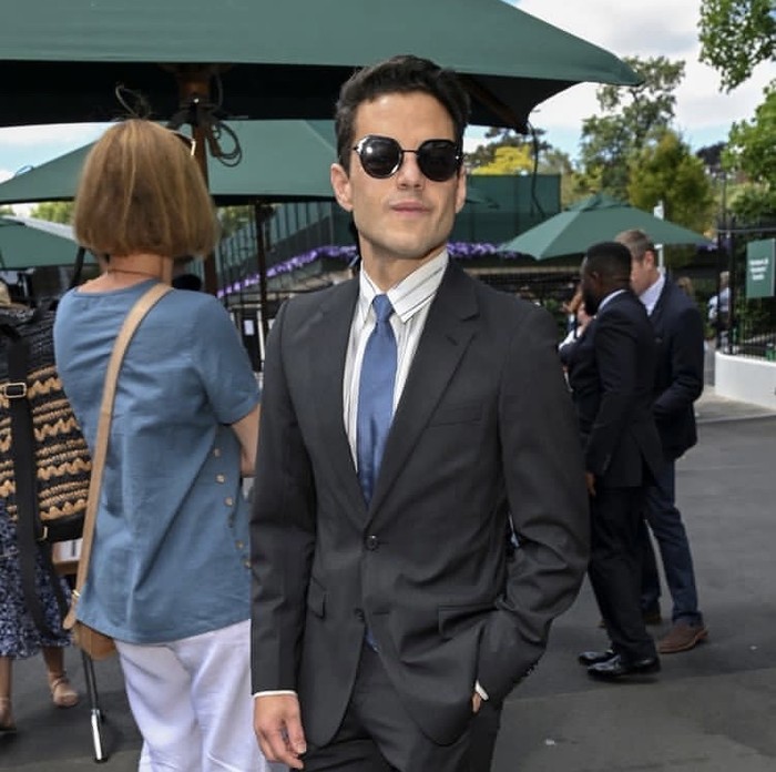 Rami Malek ditemukan dalam kerumunan penikmat Wimbledon mengenakan setelan jas hitam, dasi biru, dan sunglasses. Foto: instagram.com/wimbledon