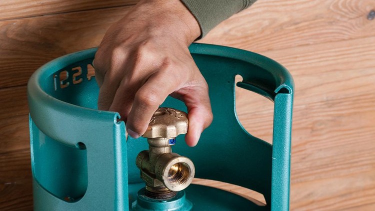 Closeup man's hand operating valve of LPG cylinder for cooking