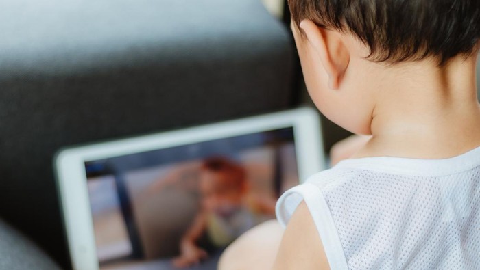 Confused aggressive Asian 2 - 3 years old toddler boy using tablet pc playing game, watching a video from tablet pc. Kids playing with tablet computer, Gadget-addicted children, pseudo-autism concept