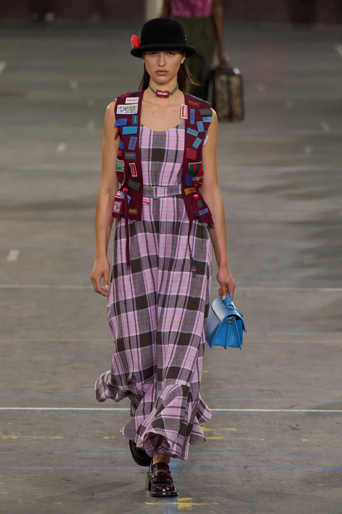 Nigo terinspirasi akan gaya sporty dan streetwear ala era '80an. Pengaruhnya terlihat pada detail patch pada vest yang dikenakan bersama maxi dress motif kotak-kotak yang berkesan rebel dan fun. Foto: Filippo Fior/Gorunway/Vogue