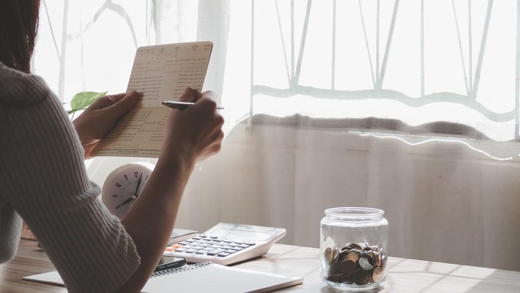 Ilustrasi Tips Keuangan saat Inflasi Women hands holding saving account passbook. financial report passbook saving money finance and business rich concept. financial problems, unemployment due to pandemic covid-19.