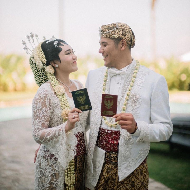 <p>Via Vallen dan Chevra Yolandi menggelar pernikahan di Surabaya, Jumat (15/7/22) pekan lalu. Pada saat akad nikah, mereka tampil kompak mengenakan busana pengantin tradisional berwarna putih. Kebaya yang digunakan merupakan rancangan desainer Didiet Maulana. Keduanya saling memperlihatkan buku nikah usai mengucap ijab kabul. (Foto: Instagram @viavallen @chevra_yo88 @yos_dandy @moirephoto)</p>