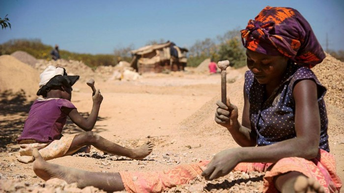 A child and a woman break rocks extracted from a cobalt mine at a copper quarry and cobalt pit in Lubumbashi on May 23, 2016. - The price of copper has fallen heavily, directly impacting workers in the town. (Photo by JUNIOR KANNAH / AFP) (Photo by JUNIOR KANNAH/AFP via Getty Images)