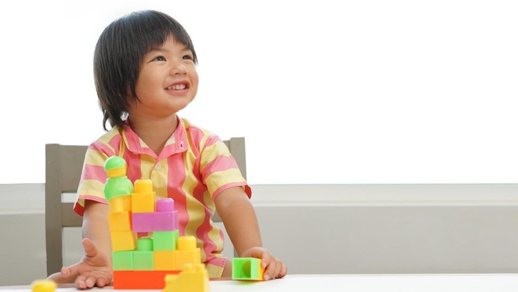 Kid playing with colorful toy blocks. Little boy building tower of block toys. Educational and creative toys and games for young children. Baby in white bedroom with rainbow bricks. Child at home