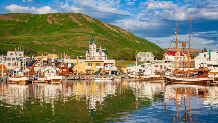 Ilustrasi Negara Paling Aman di Dunia Scenic view of the historic town of Husavik in beautiful golden evening light at sunset with blue sky and clouds, north coast of Iceland