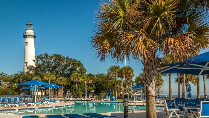 The St. Simons Lighthouse stands tall behind the public swimming pool at Neptune Park in the Village area of St. Simons Island, GA