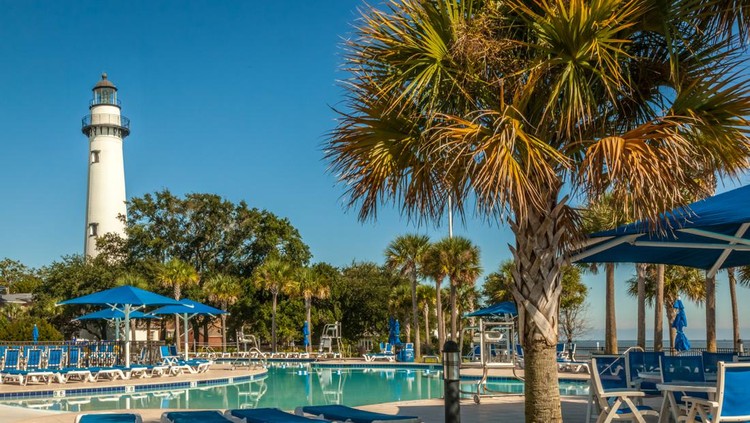 The St. Simons Lighthouse stands tall behind the public swimming pool at Neptune Park in the Village area of St. Simons Island, GA