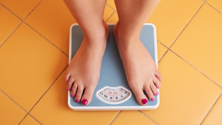 A pair of female feet standing on a bathroom scale