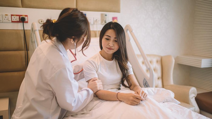 an asian female doctor listening to patient lung and heartbeat using stethoscope in the hospital ward