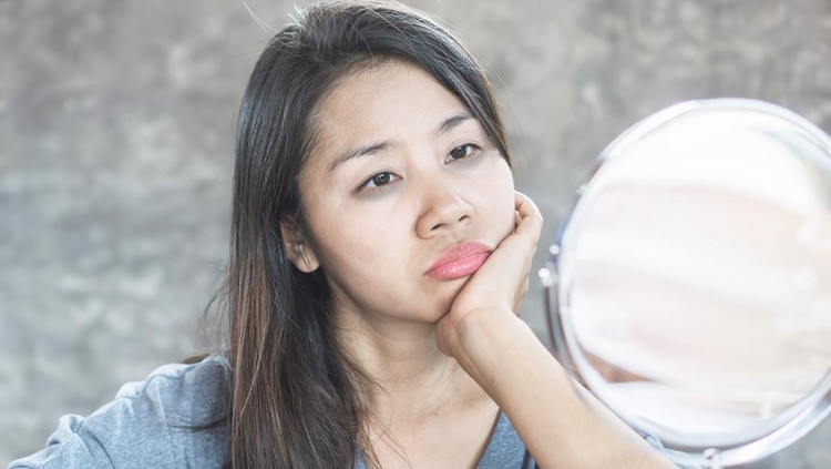 Ilustrasi Skincare Kulit Kusam dan Kering unhappy Asian woman age 40 checking her dark eyes circle problem in mirror