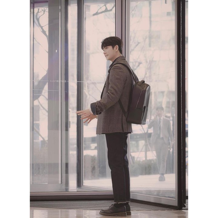 <p>Penampilan Kang Tae Oh ketika menjadi Lee Junho terlihat sederhana namun menawan. Ketika bekerja, ia terbiasa mengenakan busana formal lengkap dengan ransel berbahan kulit. (Foto: Instagram @manofcreation_official)</p>