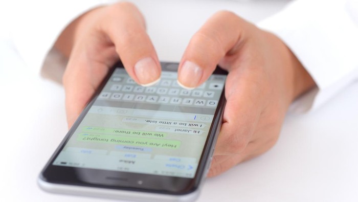 İstanbul, Turkey - July 14, 2015: Hands holding a iPhone 6 Plus displaying WhatsApp messaging application. iPhone is a touchscreen smart phone produced by Apple Inc.