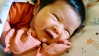 <p>Meski masih bayi, baby Mikhaila punya senyum yang manis lho Bunda. Melihat pipinya yang chubby, duh rasanya jadi enggak tahan ya pingin gendong. (Foto: Instagram @eriskarien)</p>
