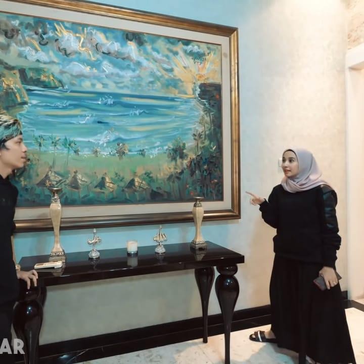 <p>Saat masuk pertama kali, Bunda akan disambut lukisan besar yang ada di dinding ruang tamu Bella. Ia mengatakan bahwa lukisan tersebut didapatkannya dari seorang pelukis asal Bali yang memberikannya secara gratis, lho Bunda. (Foto: YouTube AH)</p>