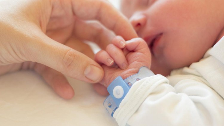 Ilustrasi Cara agar Bayi Tak Tertukar di RS Newborn baby boy sleeping in his crib, his mother's hand holding his little hand.