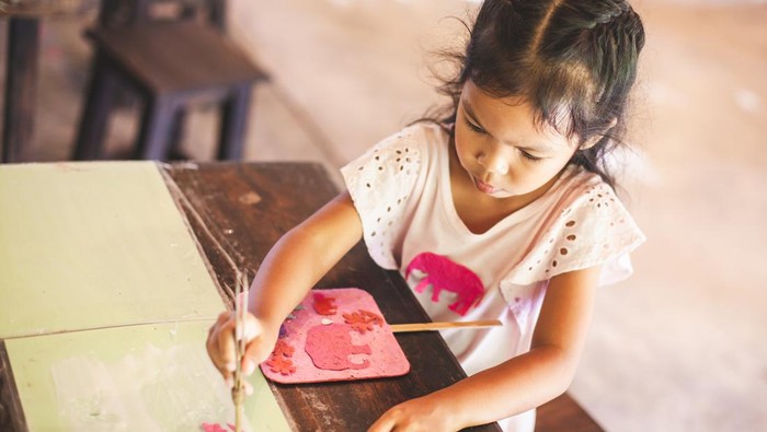 Cute asian child girl make a craft with recycling paper from poop of elephants in learning center