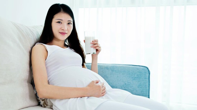 Ilustrasi Rekomendasi Susu Pasteurisasi Pregnant woman drinking milk on a sofa