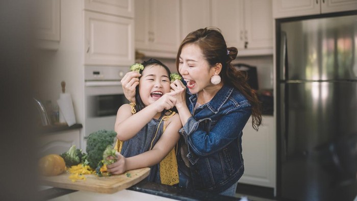 An Asian Chinese housewife having bonding time with her daughter in kitchen preparing food