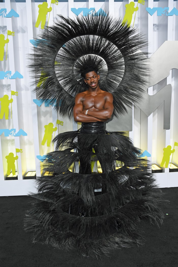 Bukan Lil Nas X jika datang tak mengenakan busana heboh. Pada MTV VMA 2022, ia memilih busana dan headpiece berhiaskan bulu karya Harris Reed. Busana serupa juga pernah dipakai oleh supermodel Iman di Met Gala 2021. Foto: PA Images via Getty Images/Doug Peters - PA Images