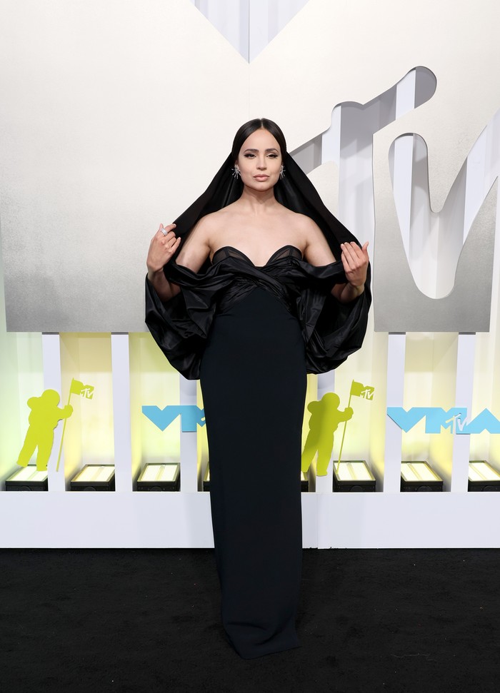 Gaya klasik juga bisa bertransformasi lebih dramatis lewat aksen hoodie. Seperti gaun Carolina Herrera yang dipakai Sofia Carson. Foto: Getty Images/Dia Dipasupil