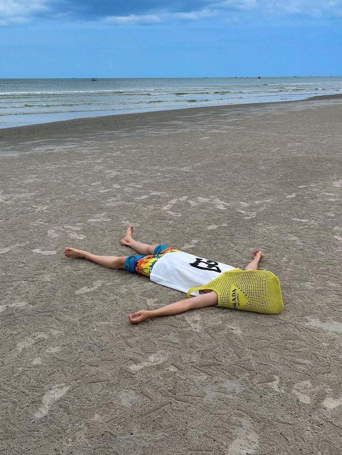Beda hingga bikin penggemar terhibur, Jae Chan DKZ punya cara unik pakai tote bag dari Prada. Sembari bersantai di pantai, penyanyi tampan ini menutupi kepalanya dengan tote bag berwarna kuning./ Foto: instagram.com/jaechan_dkz