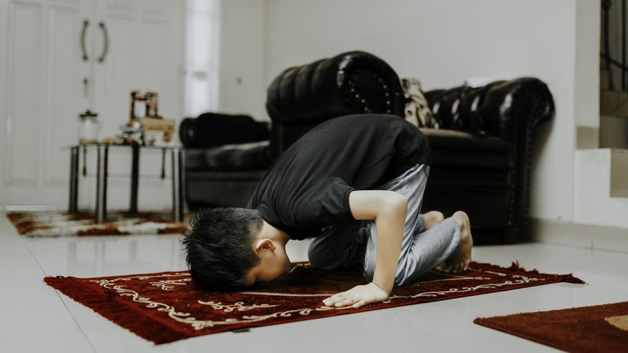 asian muslim kid is salah (doa) in home