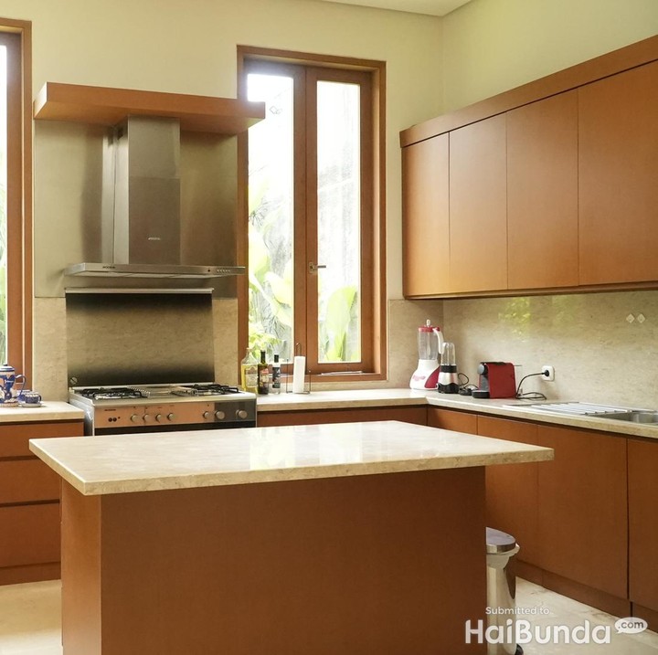 <p>Bagian dapurnya juga terlihat sederhana menggunakan desain minimalis. Hanya kitchen set berwarna kayu naturan dengan island table bernuansa senada. Tampak sangat rapi, ya, Bunda. (Foto: HaiBunda/Atmaja)</p>