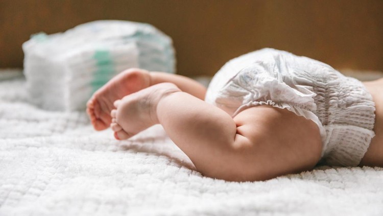 Rekomendasi Popok Bayi Newborn A baby in a diaper at the age of two months and a stack of diapers. How to choose baby diapers