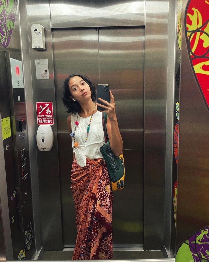 Aktris berusia 29 tahun ini juga kerap membagikan mirror selfie berbatik di lift. Outfit Putri kali ini memadukan atasan putih tanpa lengan dengan batik kombinasi merah dan coklat. / foto: Instagram.com/putrimarino
