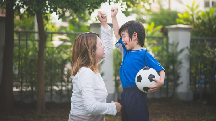 Asian mother and son Playing Soccer In Park Together