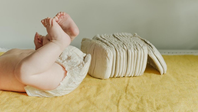 Baby wearing a white reusable diaper. Baby taking care and hygiene concept.