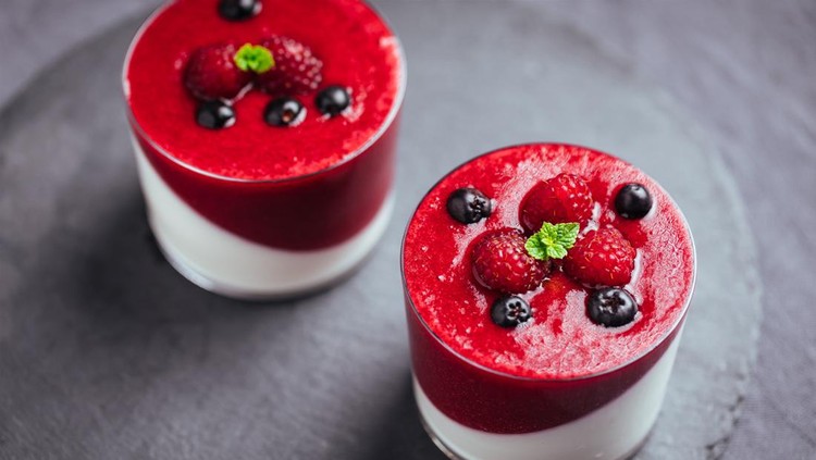Fresh Italian dessert Panna Cotta with raspberry, cherry, strawberry sauce served with raspberries, aronia, blueberry on gray background