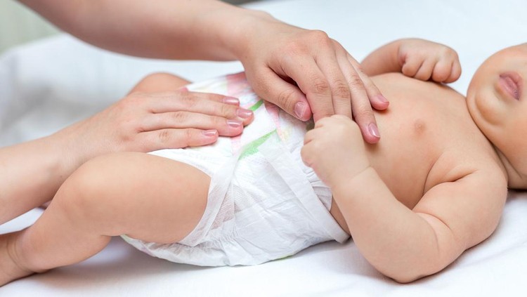 Mother changing a diaper of her newborn at home