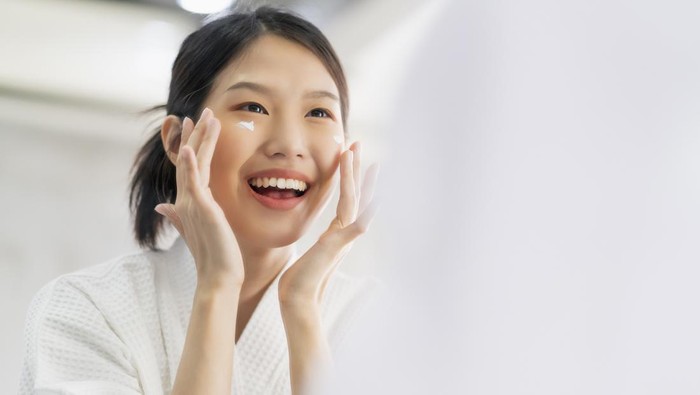 attractive freshness asian woman clean face fresh water with care look to mirror in bathroom home background