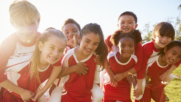 Kids in elementary school sports team piggybacking outdoors