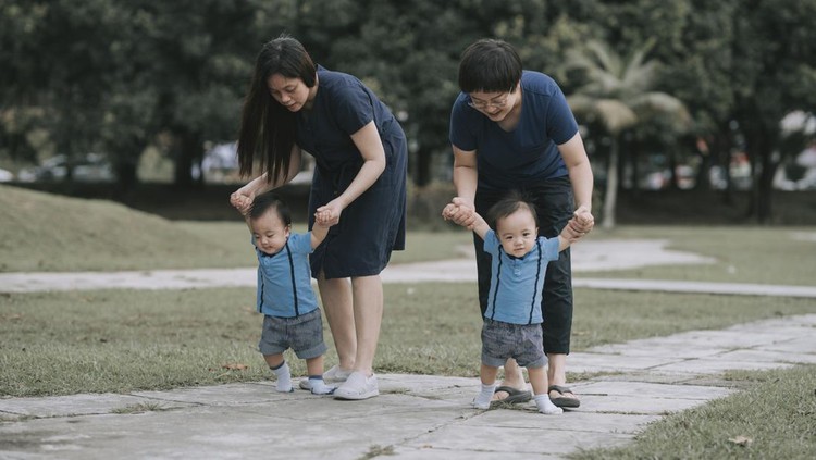 asian chinese parent with their baby boy at public park learning first steps baby walking weekend morning